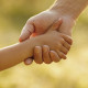 a the parent holds the hand of a small child